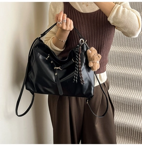 Detail of black faux leather tote with golden hardware and cute bear plush charm