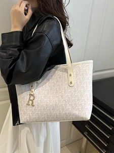 White monogram tote bag with gold logo pendant and slim handles for stylish daily commute