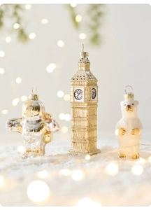 Detailed ornaments of silver astronaut, gold Big Ben, and polar bear on snow
