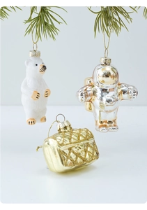 Detail of polar bear, astronaut, and quilted bag Christmas ornaments on pine branches