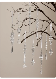 Detalle de carámbanos de acrílico transparente y adornos de perlas en una rama rústica