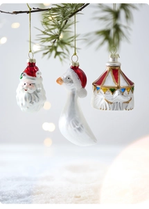 Detailed close-up of glass Santa, goose, and circus tent ornaments on a snowy pine tree