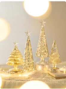Champagne glass Christmas trees with LED lights and textured glass on a festive desk