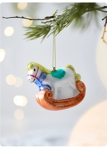 Close-up of a rocking horse Christmas ornament hanging on a pine branch with bokeh lights