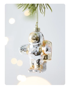 Close-up of glass astronaut Christmas ornament hanging on tree branch with warm bokeh
