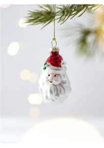 Detail of Santa Claus glass ornament with red hat and white beard hanging on Christmas tree