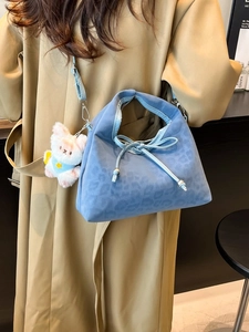 Sac fourre-tout bleu léopard avec breloque ours porté par un mannequin en trench-coat