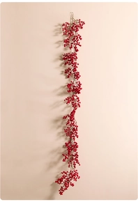Close-up of artificial red berry garland hanging on wall with realistic textures