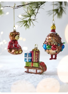 Detail view of festive Christmas ornaments featuring a bear, hedgehog and gift sled decor