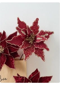 Détail d'un poinsettia de Noël en velours rouge avec paillettes dorées scintillantes