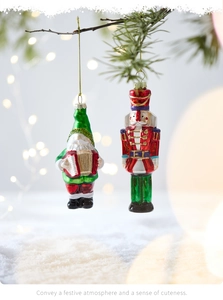 Detail showing hand-painted glass gnome and nutcracker ornaments hanging on a snowy tree