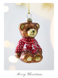 Detailed view of a glass Christmas bear ornament in a red sweater with golden cord