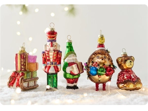Close-up of painted glass Christmas ornaments including Nutcracker and Santa on faux snow