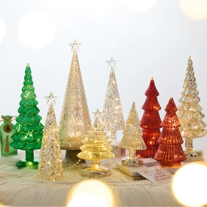 Champagne glass Christmas trees with warm LED lights on a white plush surface