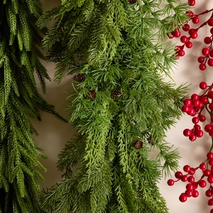 Norfolk pine Christmas garland with green needles, natural pinecones, and red berries