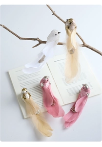 Detail of pink and white glittered foam birds with long feathers on rustic branches