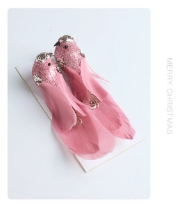 Close-up of pink Christmas feather birds with gold glitter and Merry Christmas text