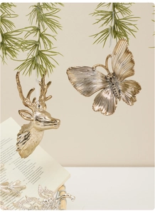 Detail of golden reindeer and butterfly ornaments hanging on pine branch for Christmas
