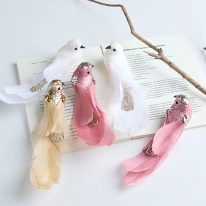 Pink and white feathered bird ornaments with glitter details on a rustic wooden branch