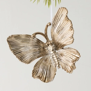 Golden butterfly Christmas tree ornament with metallic texture hanging on pine needles