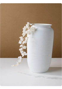 Detail of handcrafted pearl flower hair vine with gold wire on a white ceramic vase