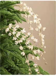 Close-up of white festive floral picks with gold beads hanging on green pine branches