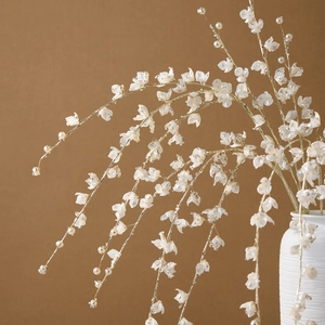 Elegant gold Christmas decorative branches with white petals and pearls in white ceramic vase
