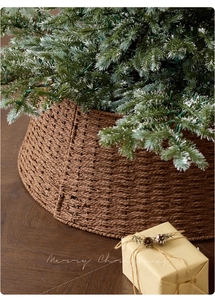 Close-up of woven brown rattan Christmas tree collar with holiday gifts on wood floor