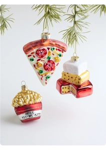 Detailed view of pizza, cake and fries glass ornaments on green pine branches