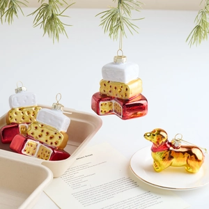 Handcrafted glass Christmas ornaments featuring cake and dachshund shapes on white background