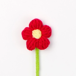 Dettaglio di un fiore a sbuffo rosso fatto a mano all'uncinetto con stelo verde