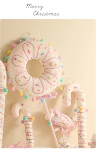 Detail von makronenfarbenem Stoff-Weihnachtsschmuck wie Lebkuchenmann und Zuckerstangen