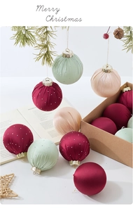 Detalle de bolas de Navidad de terciopelo rojo y verde con cristales en mesa festiva