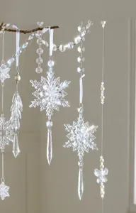 Detalle de copos de nieve de acrílico transparente y cadenas de perlas en ramas