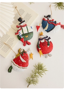 Detail view of four hand-painted metal snowman ornaments with vintage rustic textures