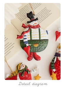 Detail view of retro metal snowman ornaments with red scarf and hat on book