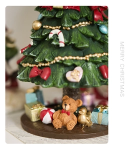 Macro detail of a resin Christmas tree base with festive bear, birds and gift boxes