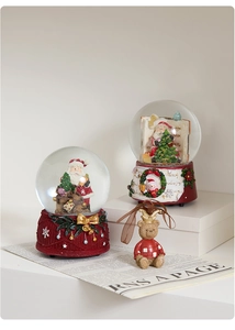Detailed Christmas resin figurines featuring snow globes and bear on a vintage newspaper
