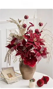 Close-up of burgundy velvet flowers and gold festive stems in a brown ceramic vase