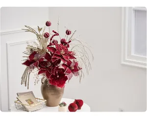 Close-up of burgundy poinsettia flowers with golden branches in a vintage metal vase
