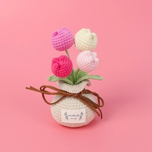 Handmade crochet tulip flower pot with four colorful blossoms in a pink setting