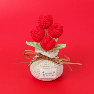 Close-up of handmade crochet red tulips in a gift bag pot with a handmade label