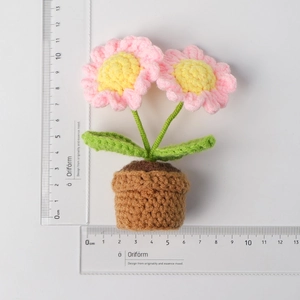 Detail shot of crochet pink forget-me-not potted plant with a scale ruler for size