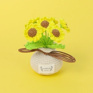 Handgehäkelte Sonnenblume im Topf mit weißer Basis und Etikett auf gelbem Hintergrund