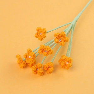 Macro detail of hand-crocheted orange flowers with pearl centers and green yarn stems