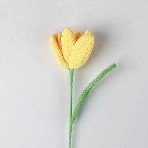 Close-up of handmade crochet yellow tulip flower with detailed knit texture and green stem