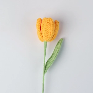 Close-up of handmade crochet tulip flower with yellow petals and green stem detail