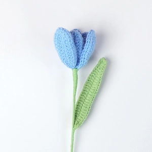 Macro shot of handcrafted light blue crochet tulip with green stem on white background