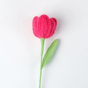 Detail of pink hand-crocheted tulip flower with soft green stem on white backdrop