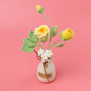 Nahaufnahme handgehäkelter gelber Rosen in cremefarbener Vase mit Hand Made Leder-Etikett